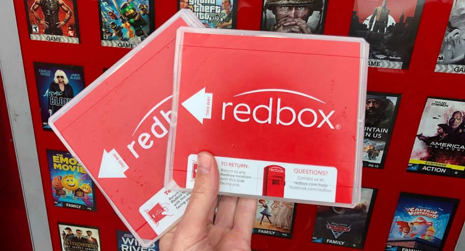 a hand holding two Redbox movie cases outside of the Redbox kiosk - free stuff on your birthday