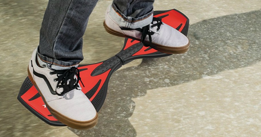 view of person's feet in sneakers sanding on a red razor ripstick