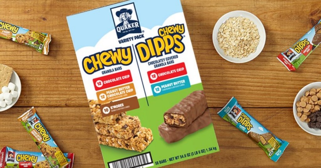 Large variety pack of granola bars on wooden surface with bowls of ingredients