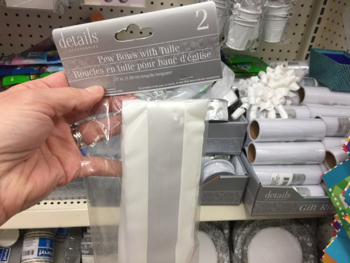 hand holding pew bows in packaging in store - dollar tree wedding