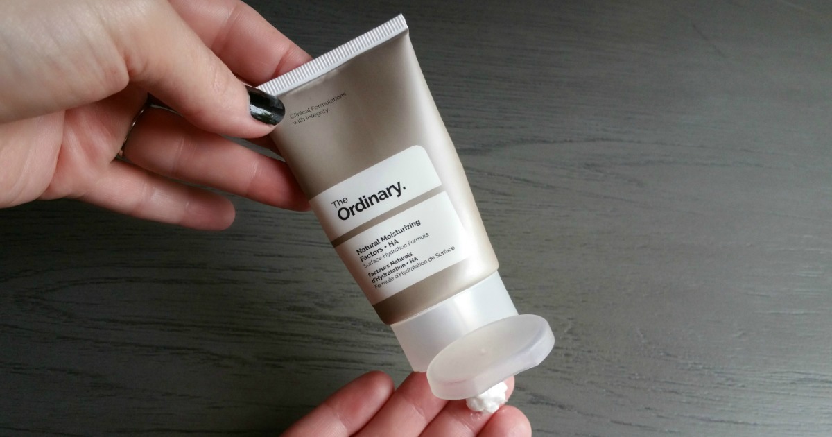 Hands holding a skincare cream and squeezing some out of the tube