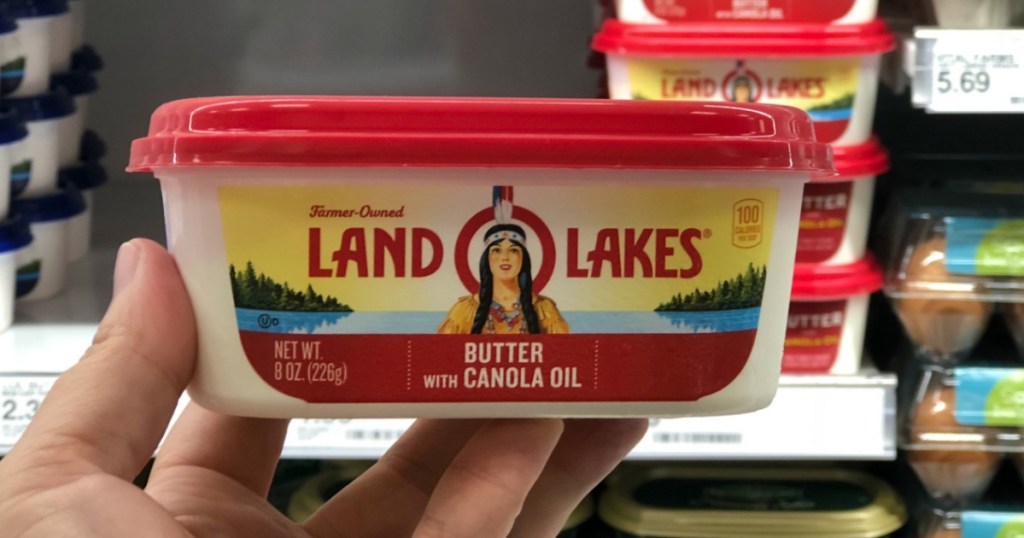 hand holding tub of butter with red lid 
