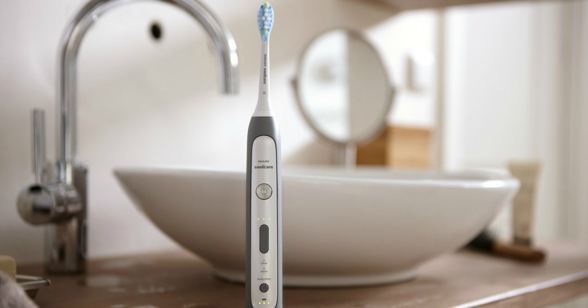 grey sonicare toothbrush sitting on counter with bathroom sink blurred in background