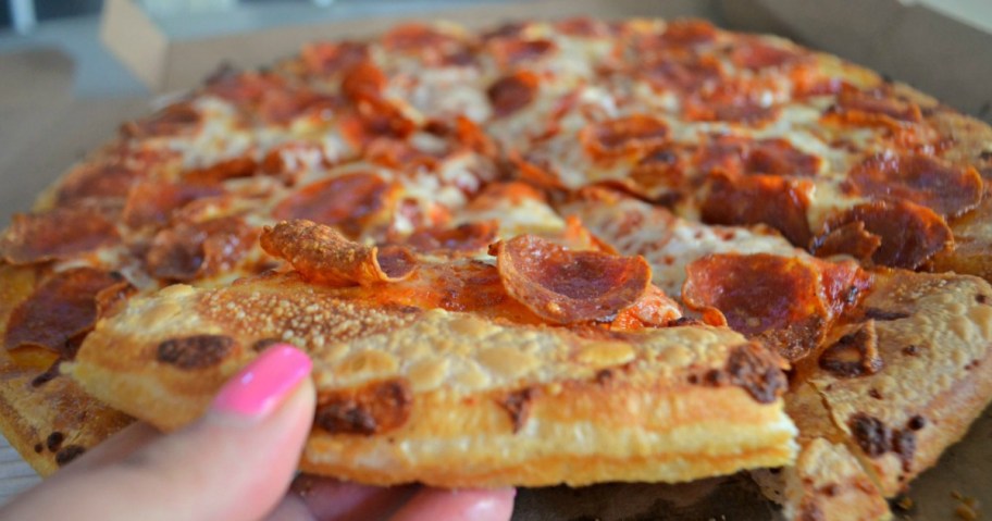 hand grabbing piece of pizza out of delivery box