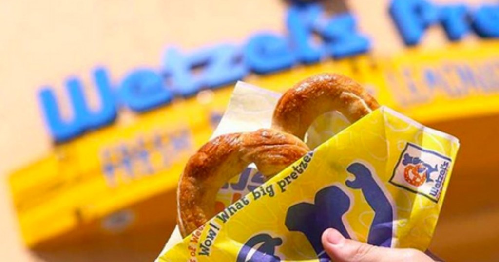 hand holding up a free pretzel in front of wetzel's pretzels sign