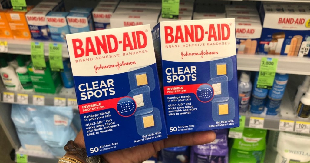 hand holding two band aid clear spot bandages at the store 