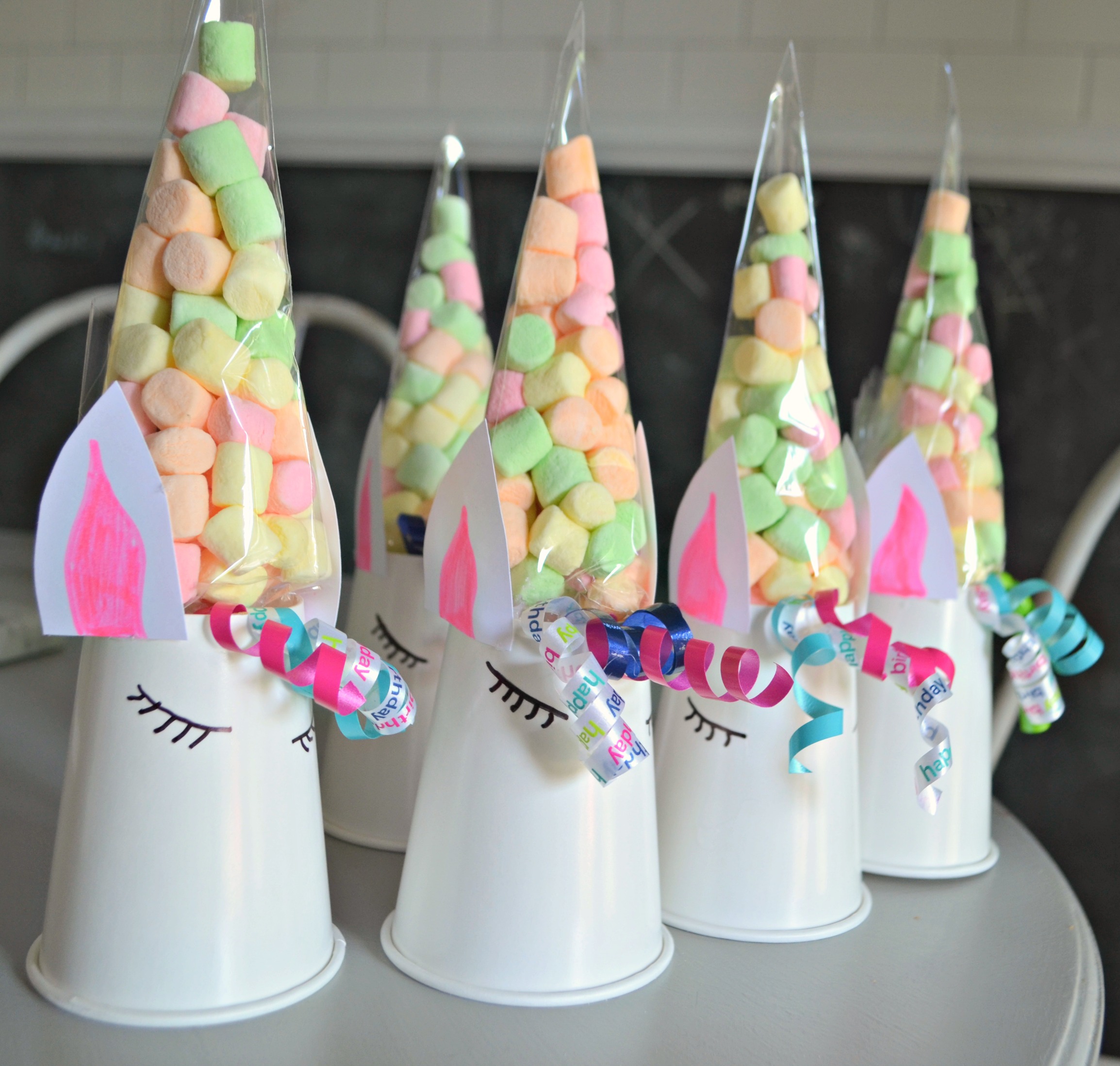 cone bags full of marshmallows on top of decorated white cups