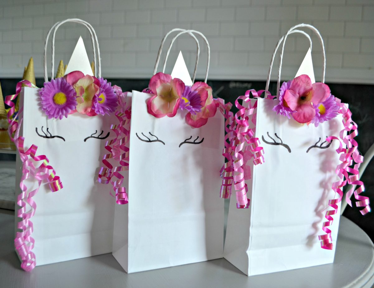 three white bags decorated with pink ribbons and flowers