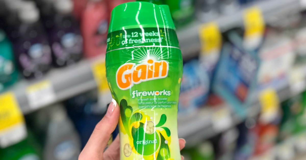hand holding a bottle of gain fireworks scent booster in front of a blurry store shelf