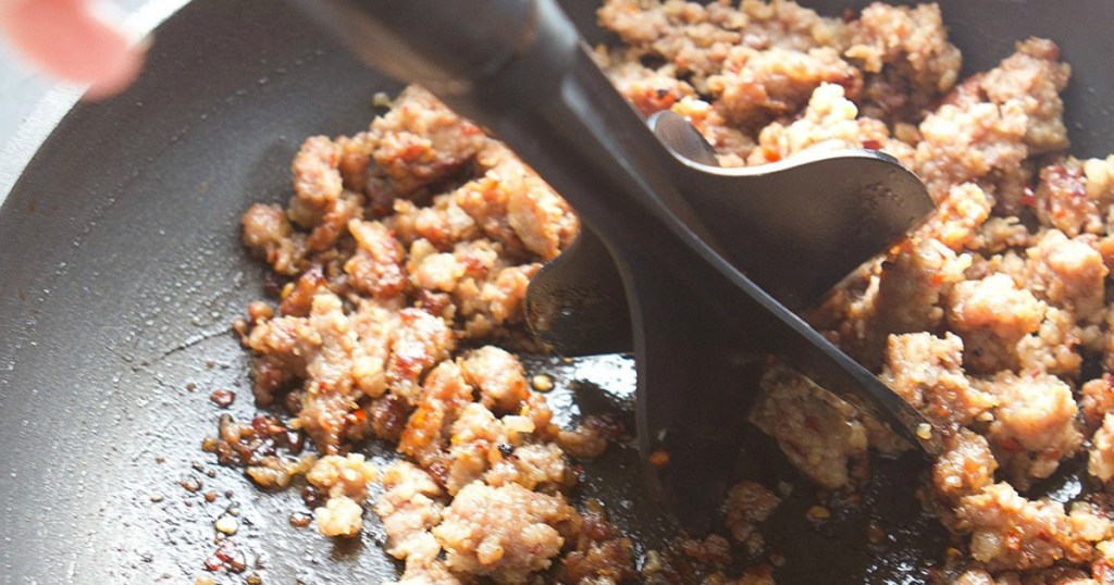 meat chopper pushing on ground beef in pan 