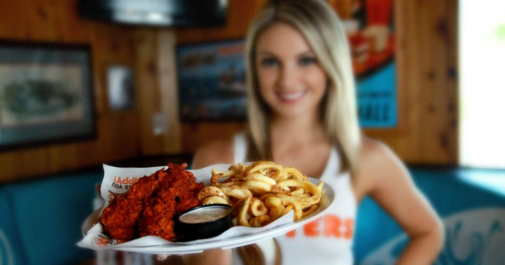 waitress holding a meal of wings and fries