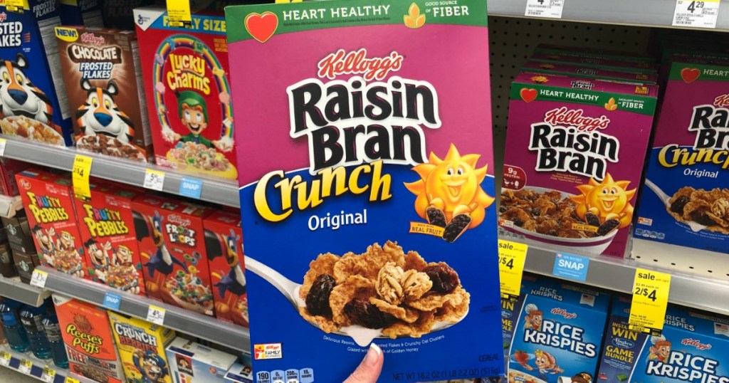 hand holding box of cereal in front of store display
