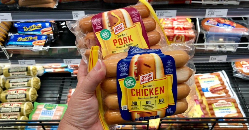 hand holding two packs of hot dogs