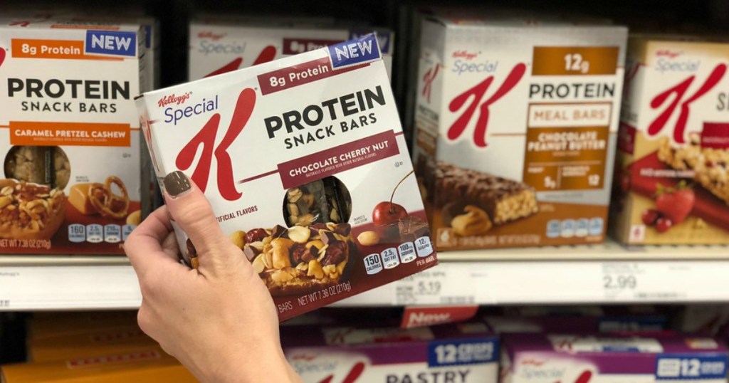 hand holding protein bars in front of shelf 