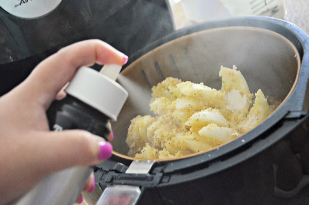 Best Air Fryer - spraying breaded onion with oil in air fryer