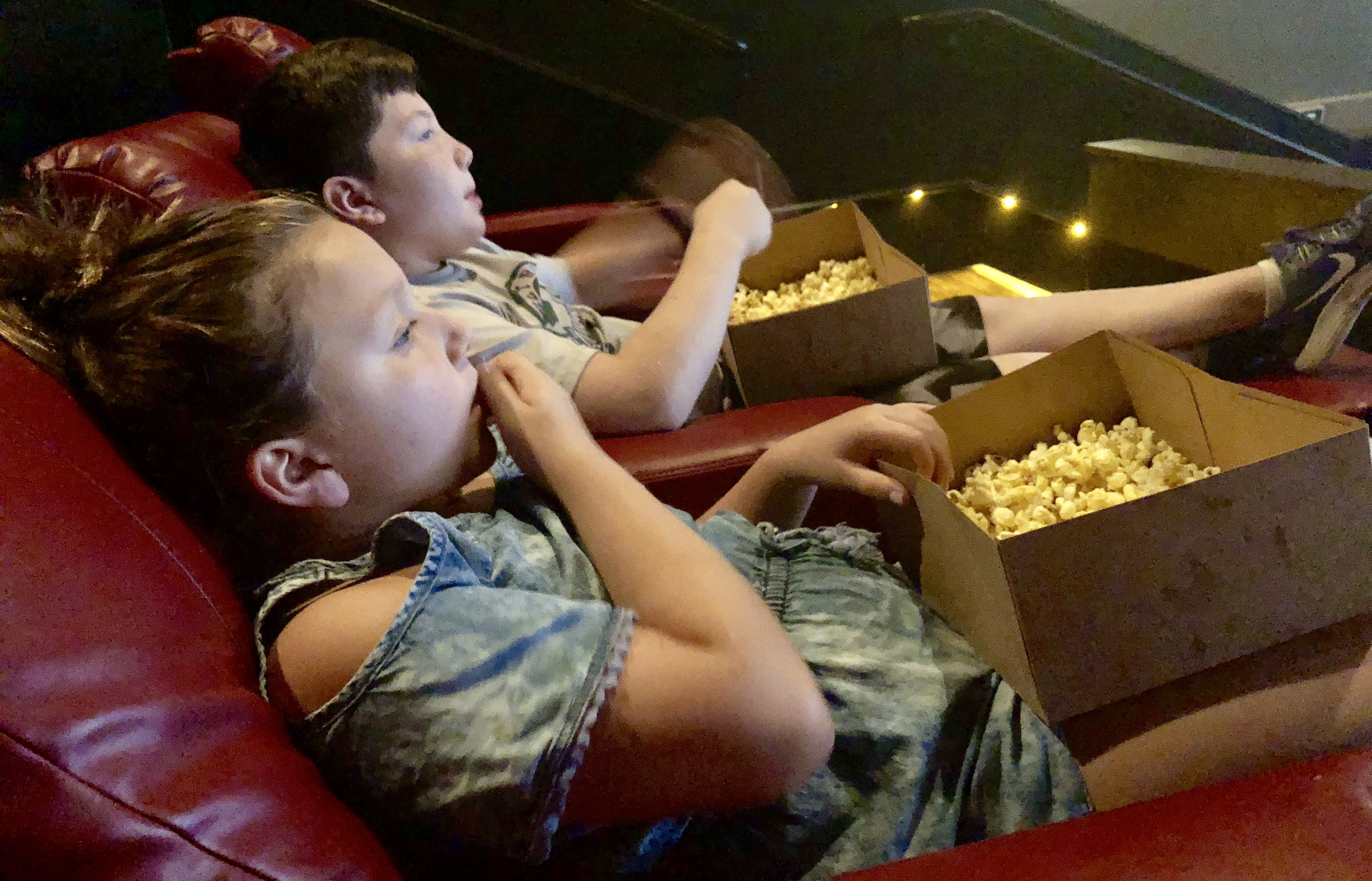 simple movie theater hacks that save money - kids with popcorn watching a movie
