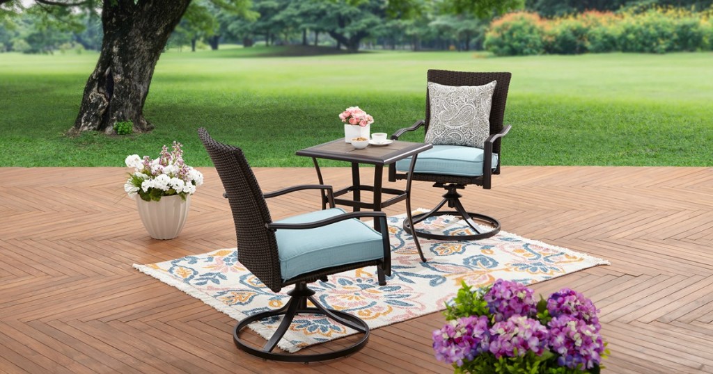 two bistro set chairs and a table, set on an outside rug