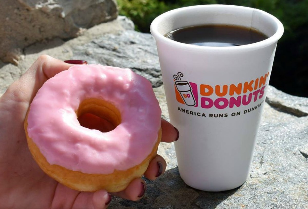 hand holding a dunkin donut with a coffee