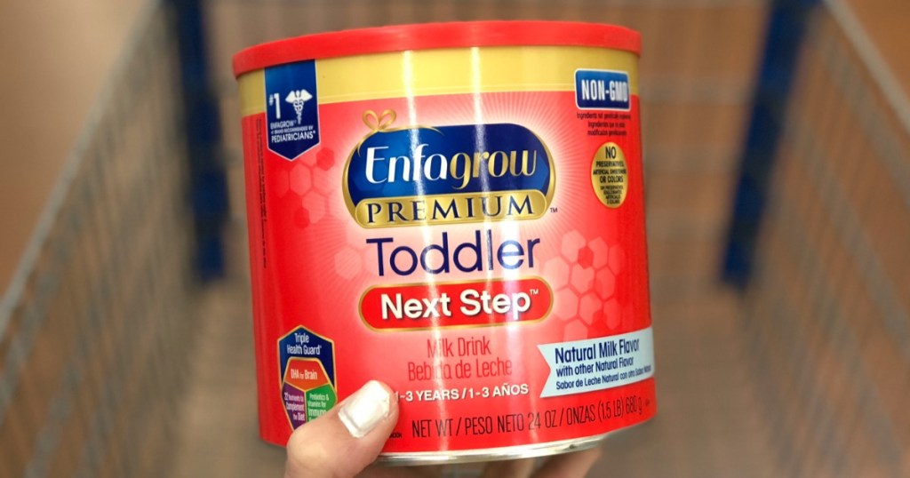 hand holding red tub of toddler formula