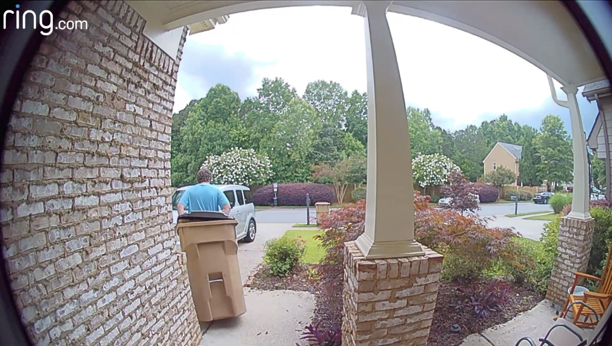 man pulling trash can away from front door of house