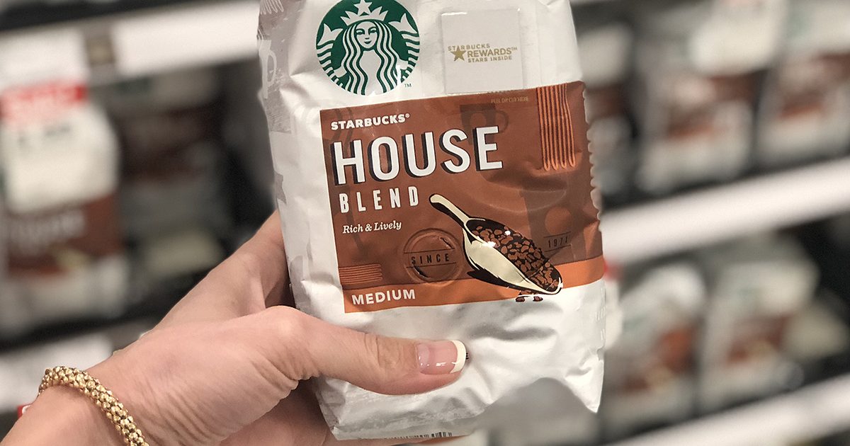 hand holding a bag of ground starbucks coffee in front of a store aisle