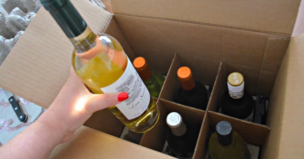 Hand holding a bottle of wine over a wine box