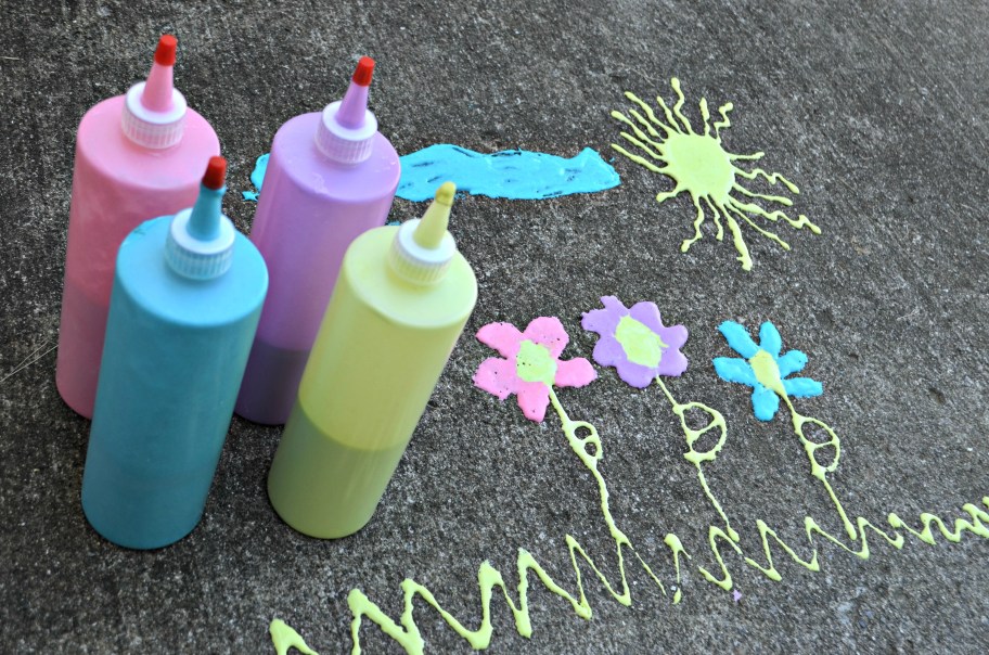 bottles of sidewalk paint on the ground next to designs