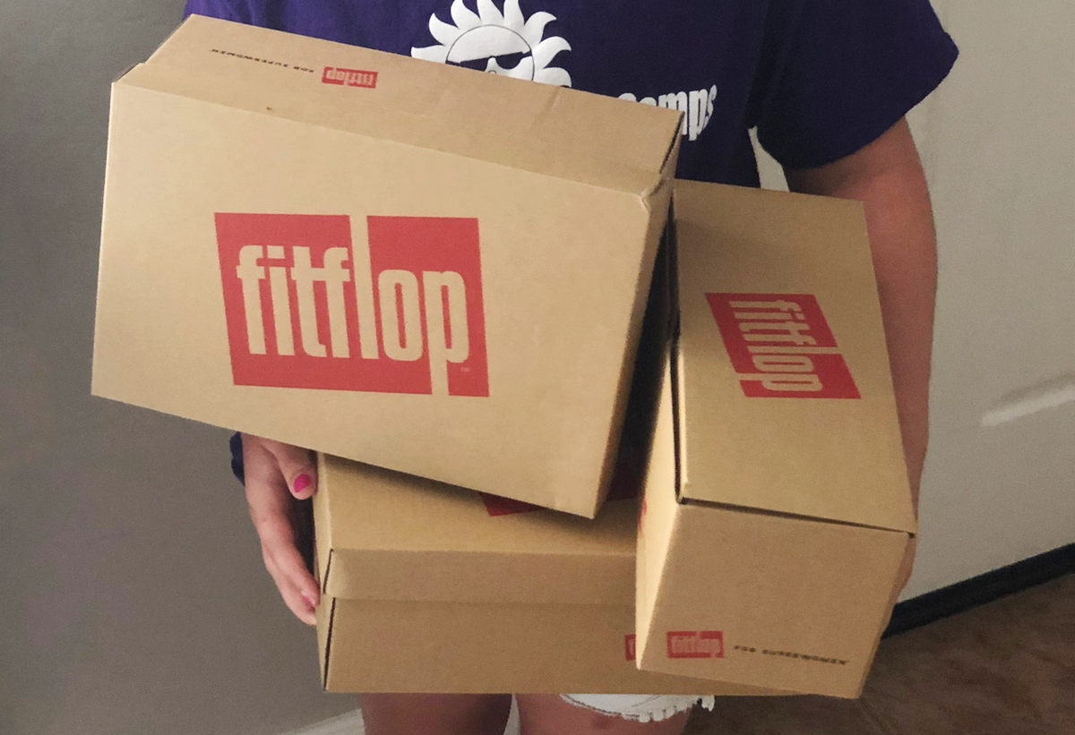 someone holding fitflop boxes