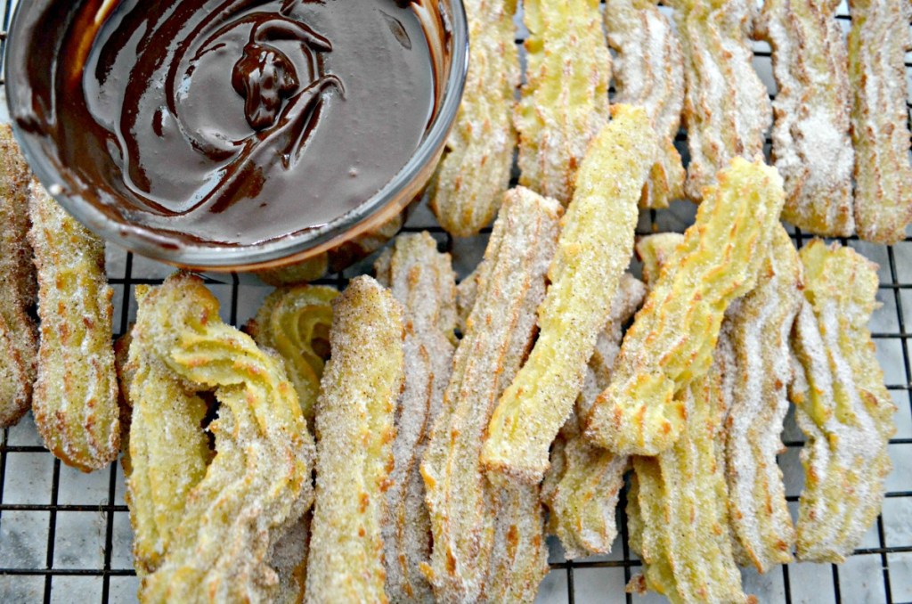 pile of homemade churros with chocolate sauce 