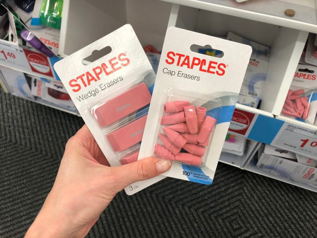 hand holding two packages of Staples erasers