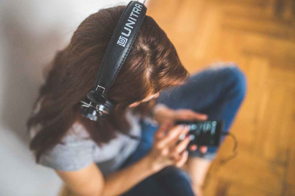 woman with headphones listening to her mobile device