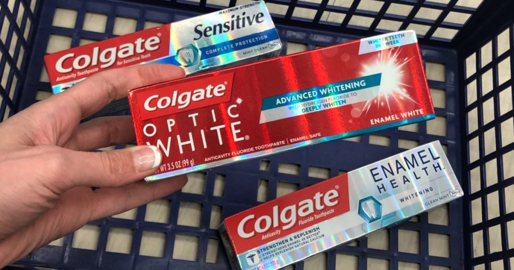 walgreens basket with colgate optic white and hand holding one box of colgate toothpaste