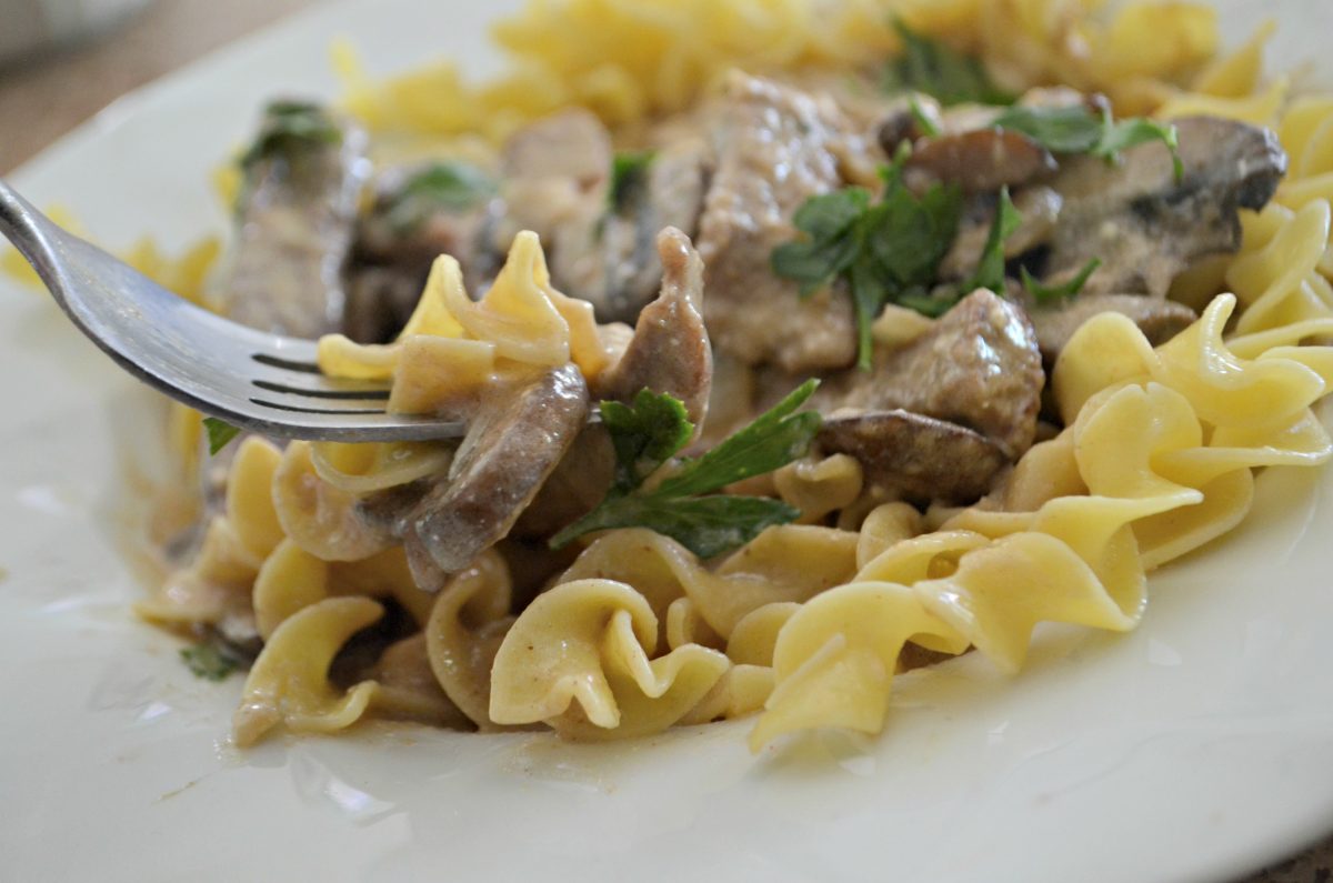 classic beef stroganoff is one of our favorite childhood recipes – a fork taking some of the finished stroganoff from the plate