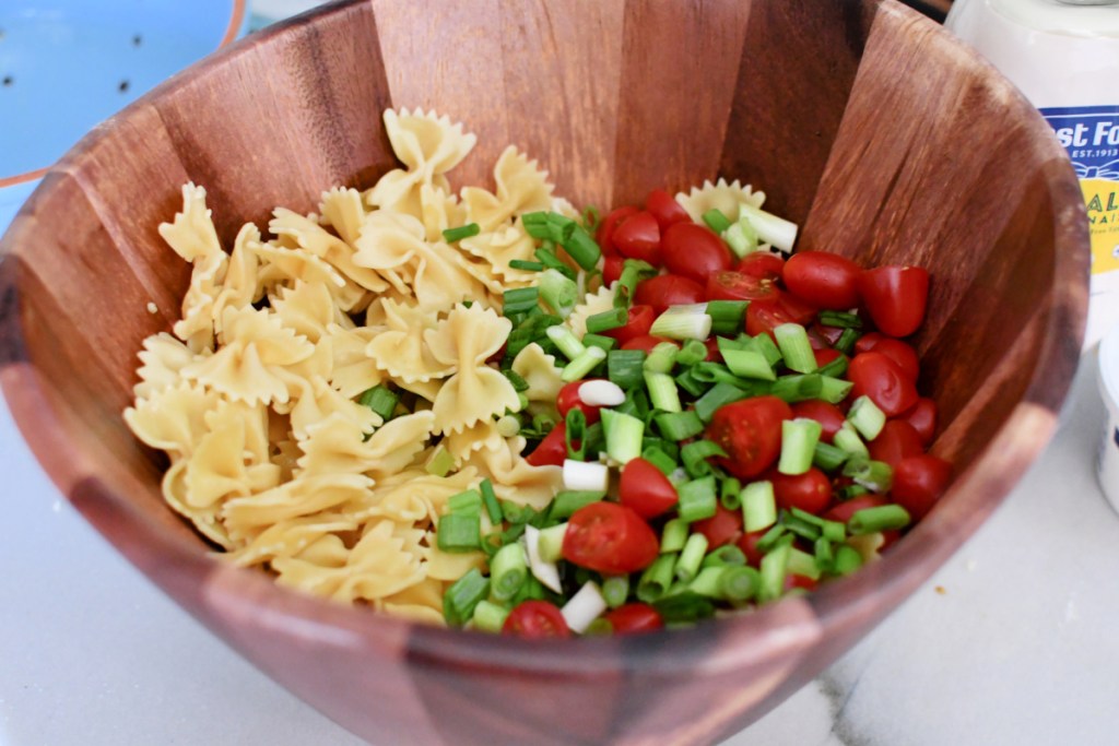 pasta and chopped veggies in a large wood salad bowl
