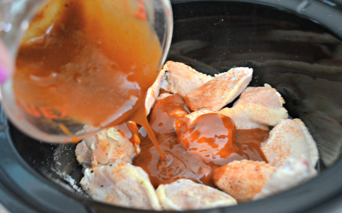 pouring sauce on wings in crock-pot