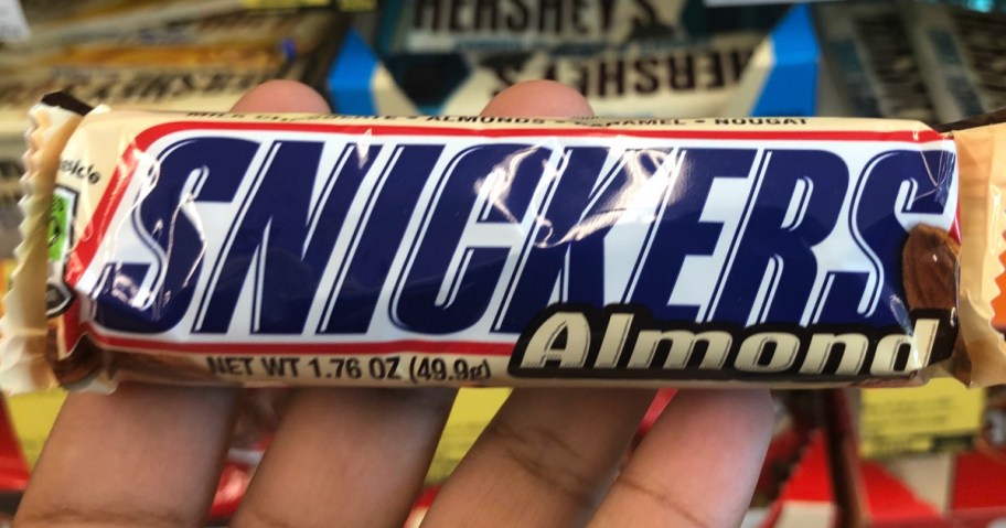 A hand holding a Snickers bar