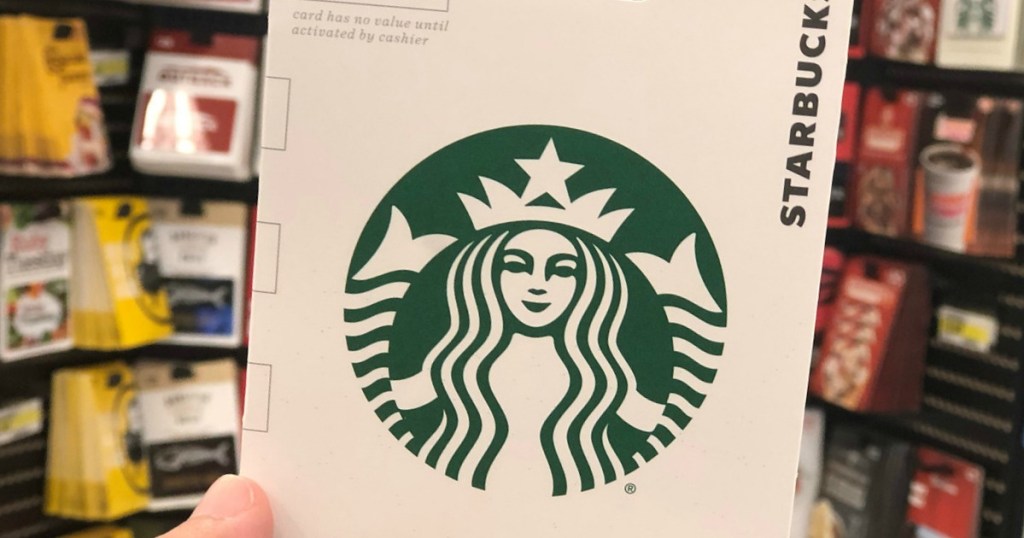 hand holding starbucks gift card with gift cards hanging in the background