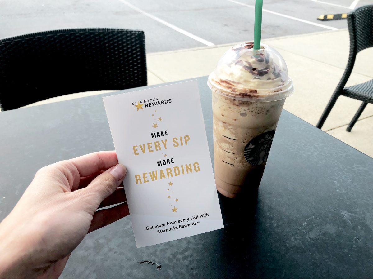 starbucks rewards in hand with drink on table