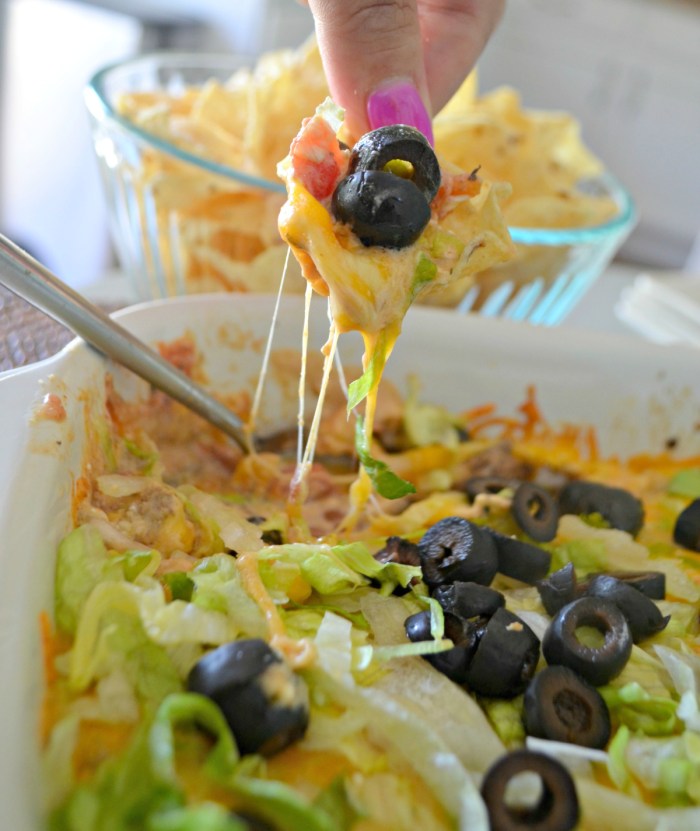 Scooping up baked taco dip with a chip.