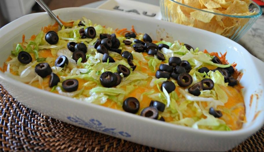 baked taco dip topped with lettuce and olives