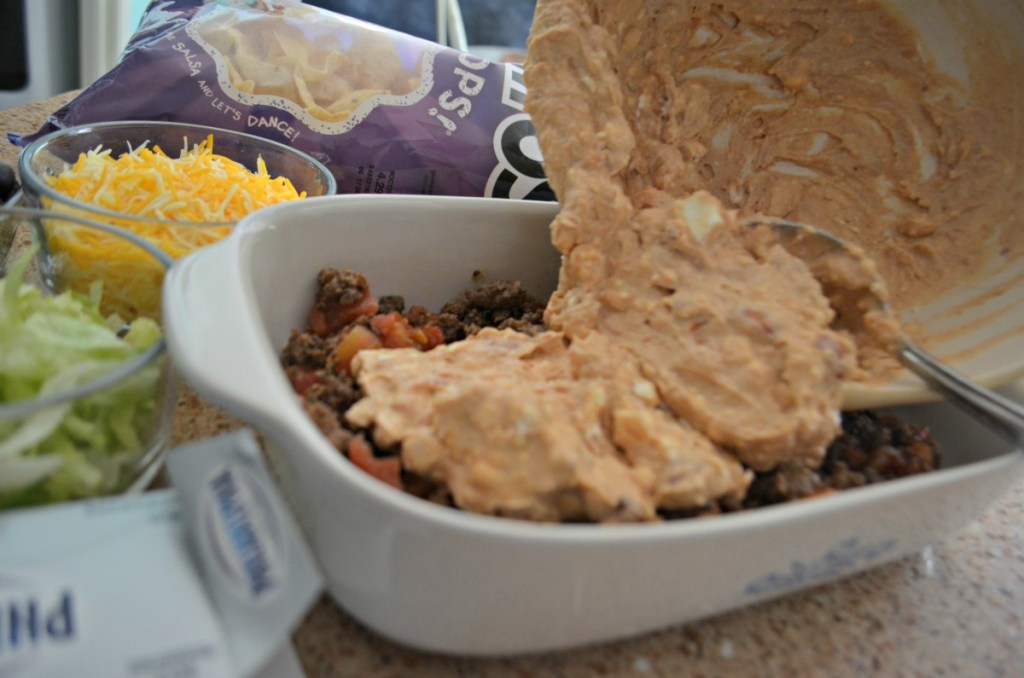 pouring refried beans into casserole dish