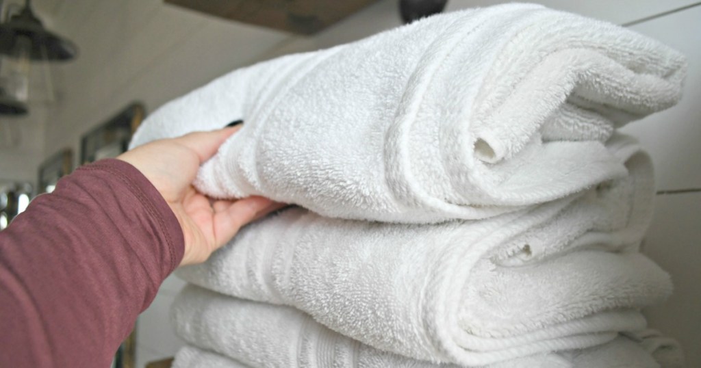 hand holding folded white bath towels