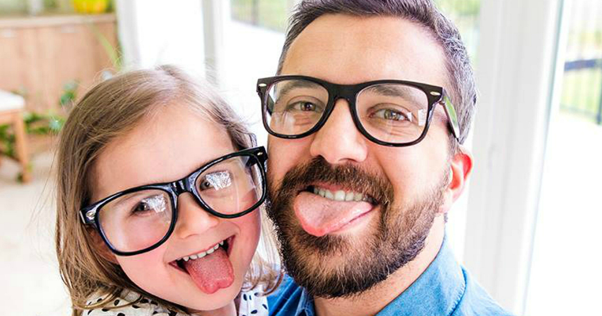 Father and daughter wearing glasses sticking tongues out