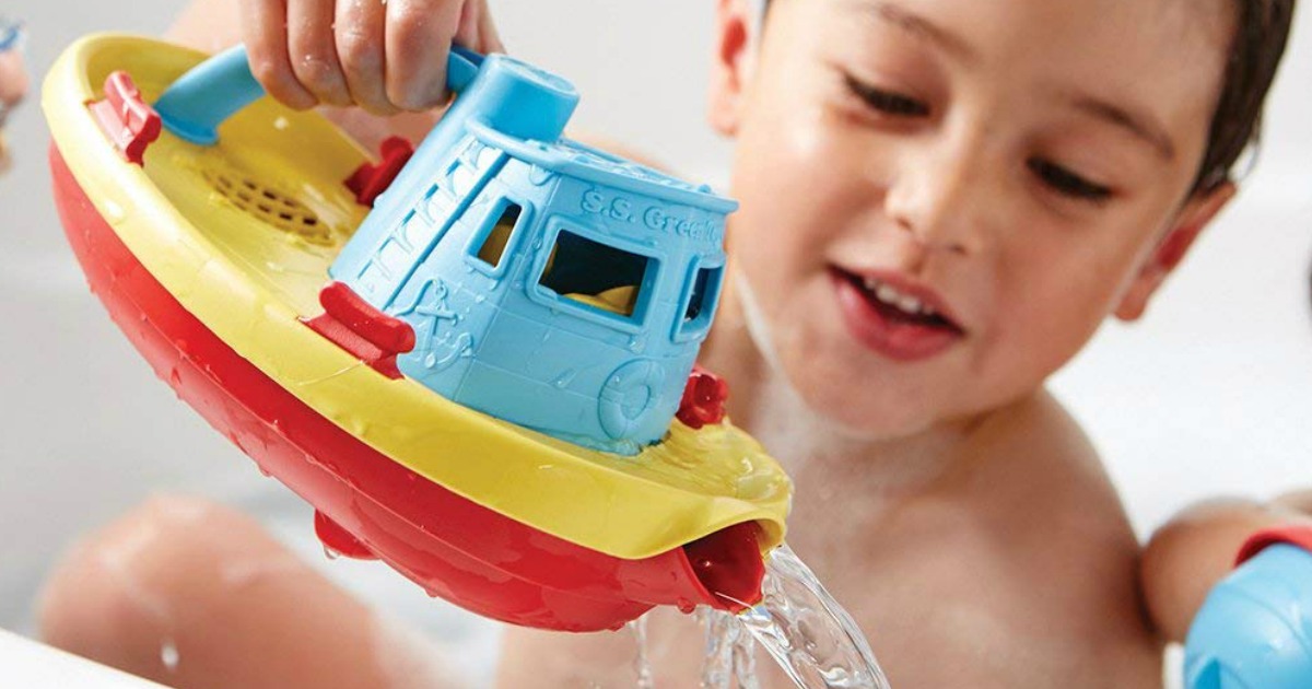 kid playing with a toy tugboat that's pouring water