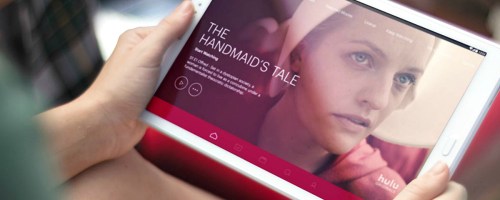 woman holding a white tablet with hulu app open showing handmaid's tale
