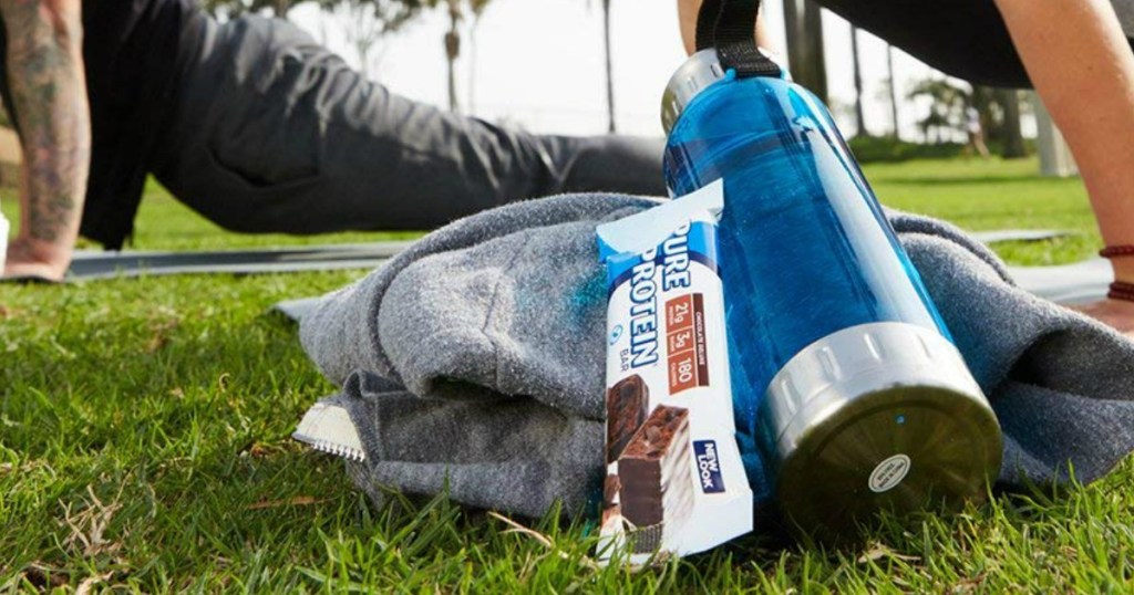 Pure Protein Bar sitting next to backpack and water bottle