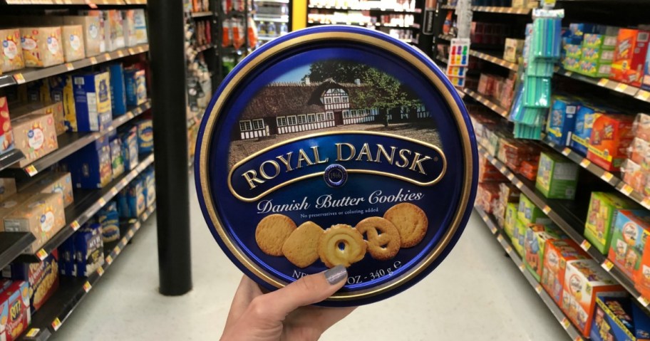 A hand holding up a tin of cookies.