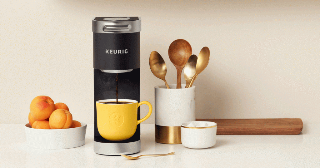 keurig espresso maker with yellow coffee cup and spoons and peaches beside machine