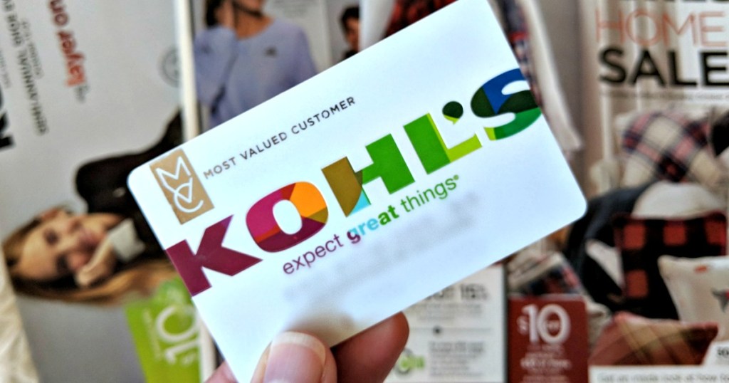 Kohl's credit card in-hand in front of Kohl's ad