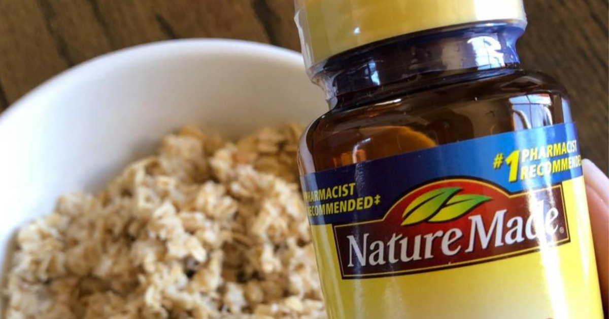 nature made vitamin bottle held in hand above bowl of oatmeal